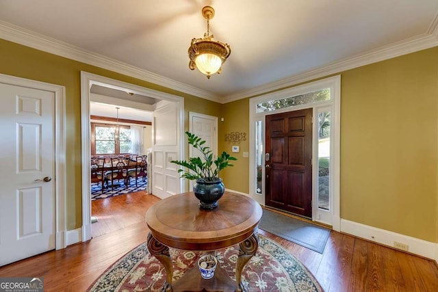 foyer entrance with ornamental molding and hardwood / wood-style floors