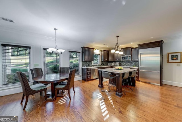 dining space with ornamental molding, a notable chandelier, and light hardwood / wood-style flooring