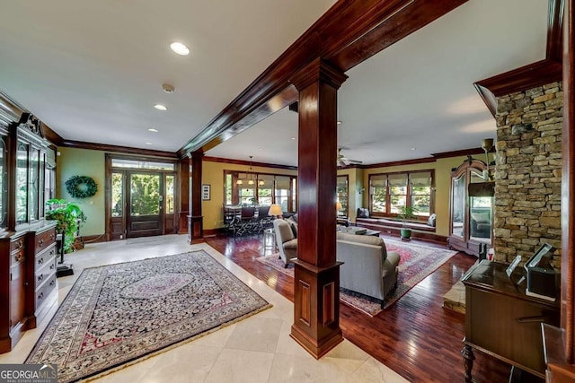 entrance foyer with crown molding, light hardwood / wood-style flooring, and ornate columns