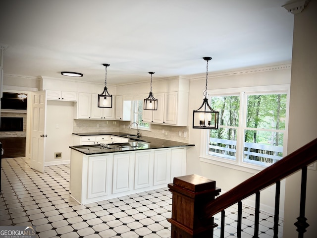 kitchen with white cabinets, decorative backsplash, sink, ornamental molding, and kitchen peninsula