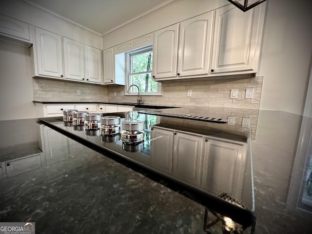 bar with crown molding, white cabinets, sink, and dark stone countertops