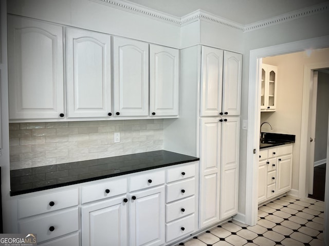 kitchen with sink, white cabinetry, backsplash, and crown molding