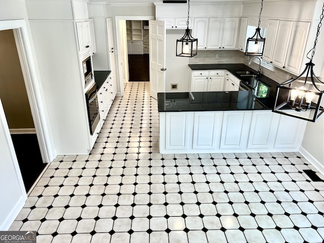 kitchen with stainless steel microwave, wall oven, white cabinetry, sink, and pendant lighting