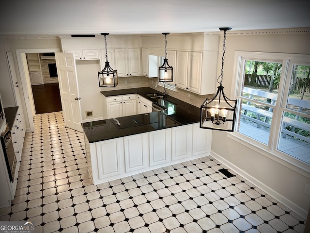 kitchen featuring sink, pendant lighting, white cabinets, and kitchen peninsula