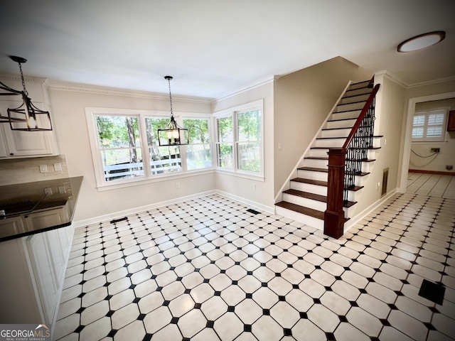 unfurnished dining area with a notable chandelier and crown molding