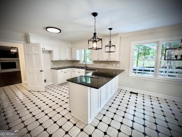 kitchen with kitchen peninsula, sink, white cabinetry, and crown molding