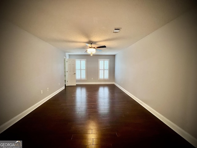 empty room with ceiling fan and dark hardwood / wood-style flooring