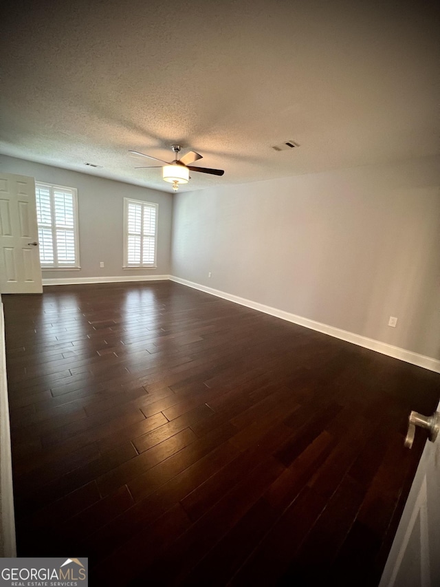 empty room featuring a textured ceiling, dark hardwood / wood-style floors, and ceiling fan