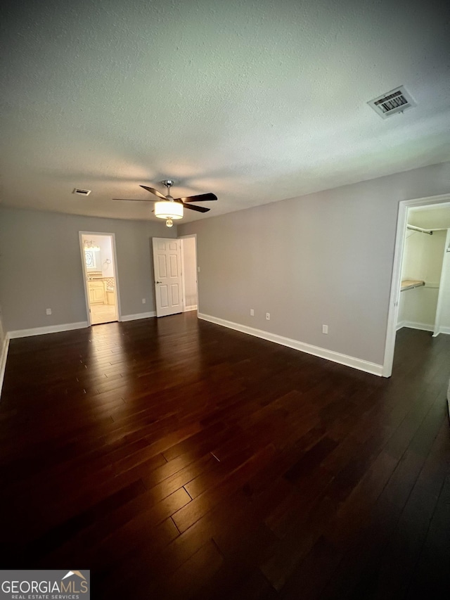 empty room with a textured ceiling, dark hardwood / wood-style floors, and ceiling fan