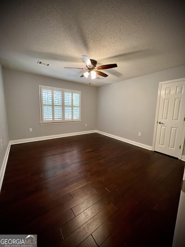 unfurnished room featuring ceiling fan, dark wood-type flooring, and a textured ceiling