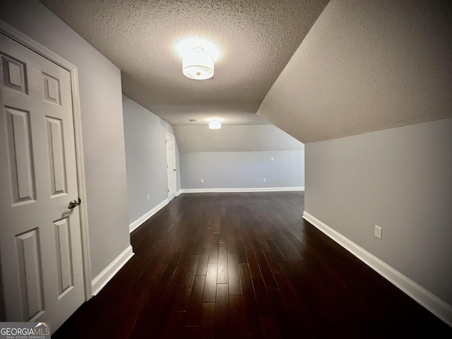 bonus room featuring dark wood-type flooring, a textured ceiling, and vaulted ceiling