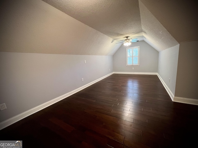 additional living space with vaulted ceiling, dark hardwood / wood-style floors, and a textured ceiling