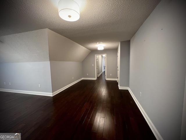 additional living space with dark wood-type flooring, a textured ceiling, and lofted ceiling