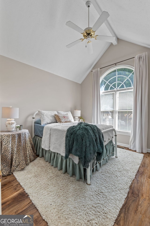 bedroom featuring wood-type flooring, vaulted ceiling with beams, and ceiling fan