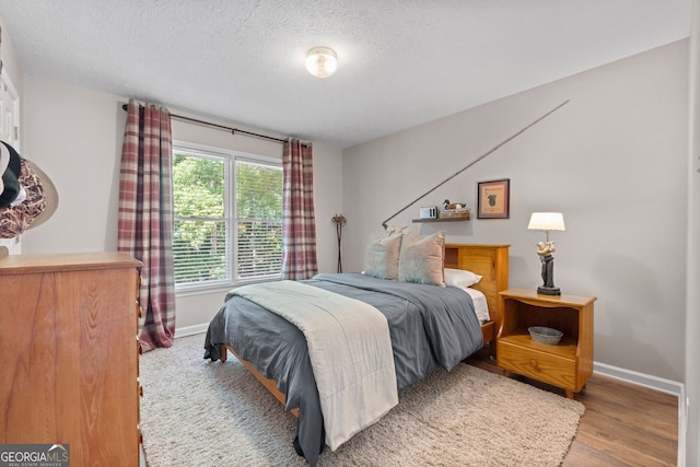 bedroom with a textured ceiling and hardwood / wood-style floors