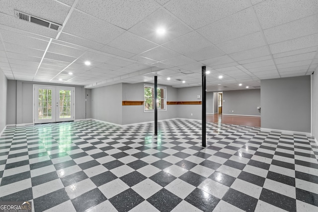 basement with tile patterned flooring, a drop ceiling, and french doors