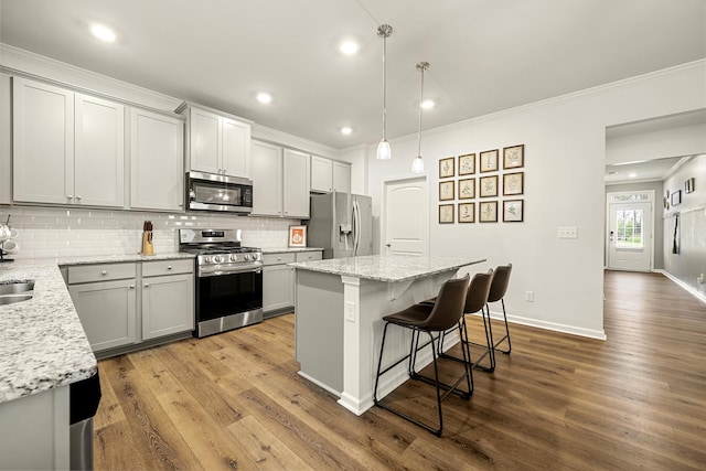 kitchen featuring pendant lighting, a kitchen island, light stone countertops, and stainless steel appliances