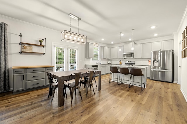 dining room with crown molding and light hardwood / wood-style flooring