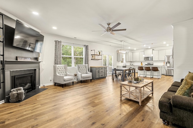 living room with ceiling fan, crown molding, and light hardwood / wood-style flooring