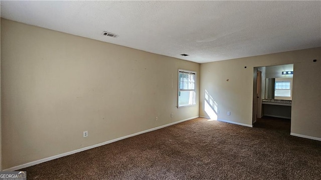 carpeted empty room featuring a textured ceiling