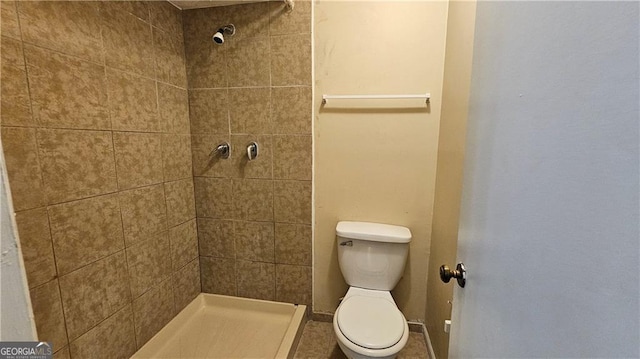 bathroom featuring a tile shower and toilet