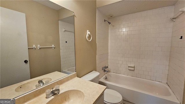 full bathroom featuring vanity, tiled shower / bath, a textured ceiling, and toilet