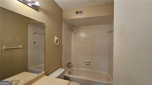 full bathroom with vanity, tiled shower / bath, a textured ceiling, and toilet