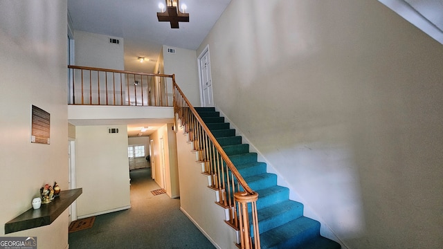 stairway with a towering ceiling and carpet