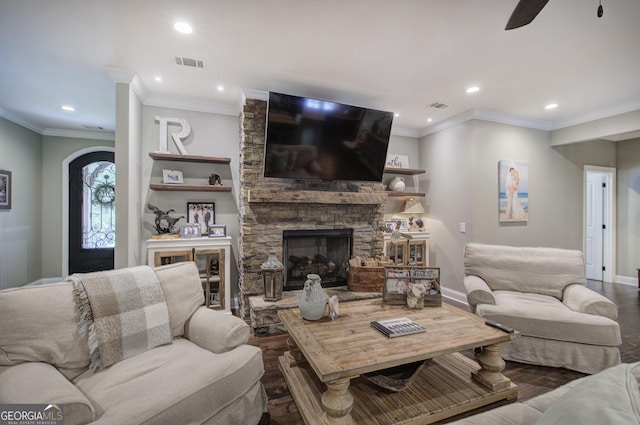 living room with hardwood / wood-style flooring, ceiling fan, a stone fireplace, and crown molding