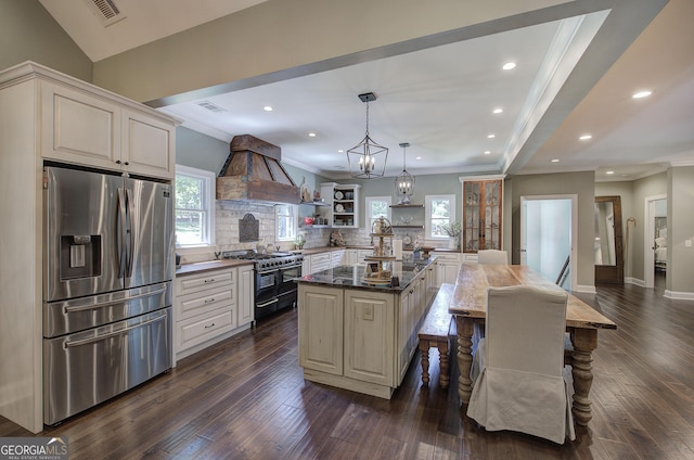 kitchen featuring double oven range, stainless steel refrigerator with ice dispenser, tasteful backsplash, decorative light fixtures, and a kitchen island