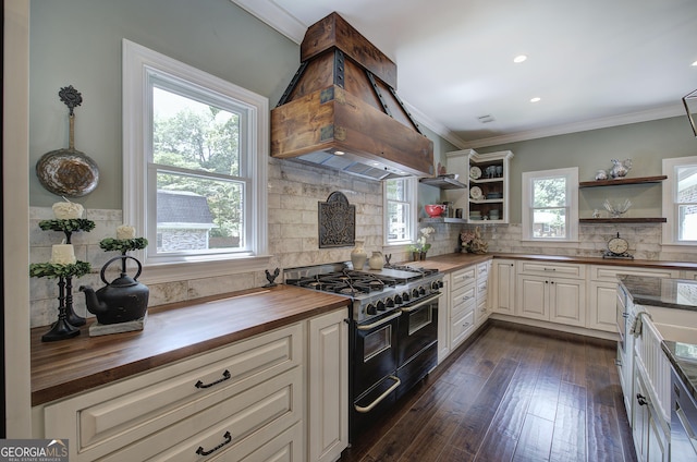 kitchen featuring custom exhaust hood, range with two ovens, dark hardwood / wood-style floors, decorative backsplash, and butcher block counters