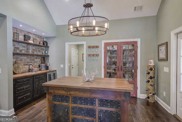 dining room with vaulted ceiling, sink, dark hardwood / wood-style floors, and a notable chandelier