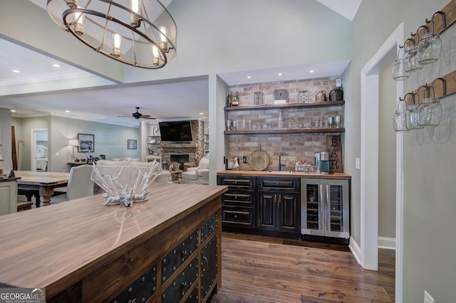 bar with butcher block counters, a fireplace, beverage cooler, and dark wood-type flooring