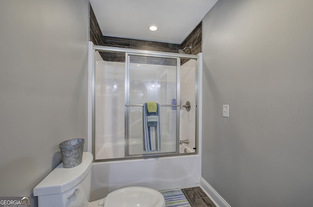 bathroom featuring combined bath / shower with glass door and toilet