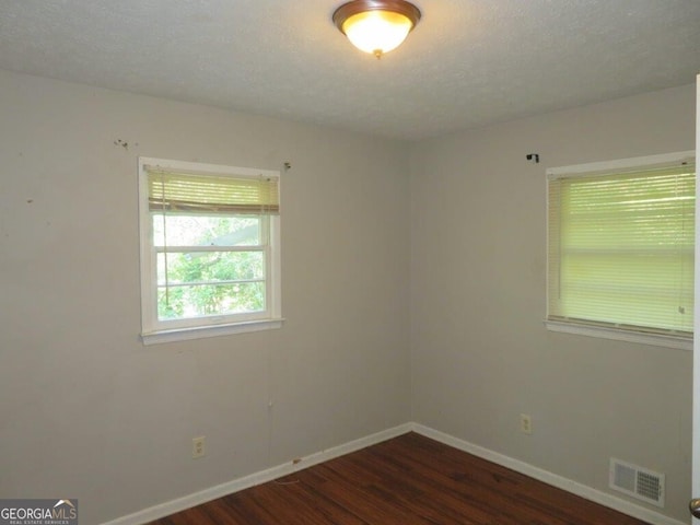 spare room with dark hardwood / wood-style flooring and a textured ceiling