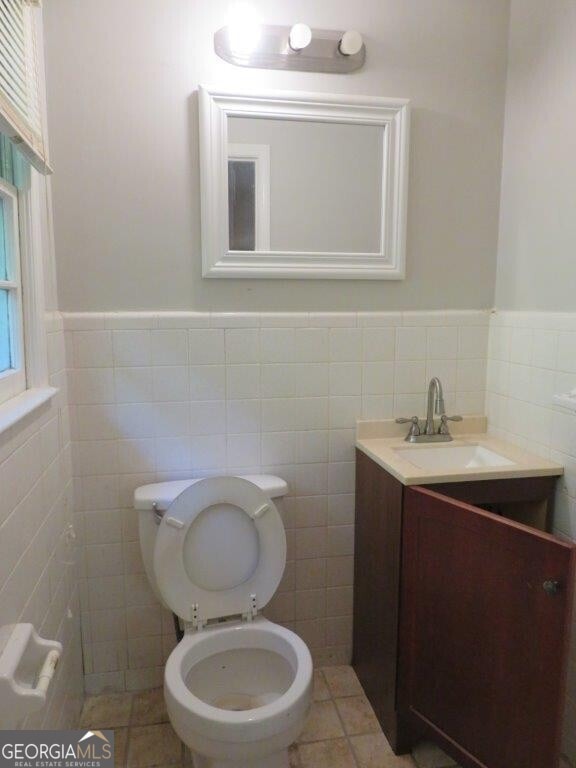 bathroom featuring tile patterned flooring, vanity, toilet, and tile walls