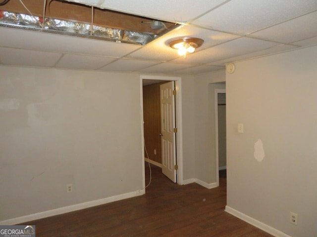 basement with a paneled ceiling and dark wood-type flooring