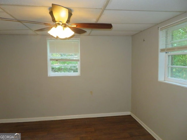 empty room with a paneled ceiling, ceiling fan, and dark hardwood / wood-style floors