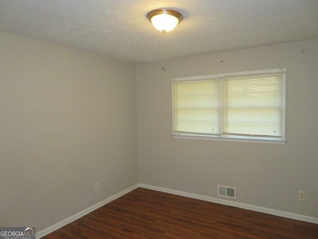 empty room with a textured ceiling and dark wood-type flooring