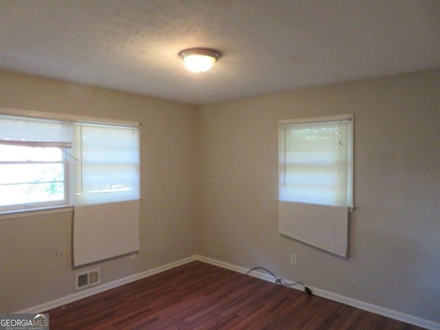 empty room featuring dark wood-type flooring and a textured ceiling