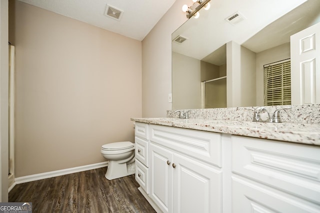 bathroom with hardwood / wood-style flooring, vanity, toilet, and a shower with shower door