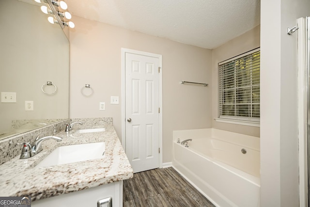 bathroom featuring vanity, a tub to relax in, hardwood / wood-style flooring, and a textured ceiling