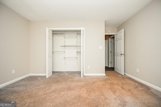 unfurnished bedroom with light carpet, a closet, and a textured ceiling