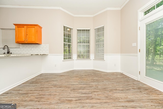 unfurnished dining area with ornamental molding, sink, and light wood-type flooring