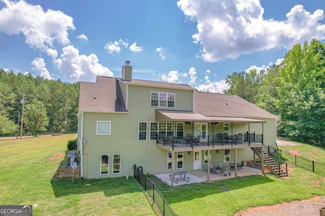 back of house featuring a patio, a wooden deck, and a yard