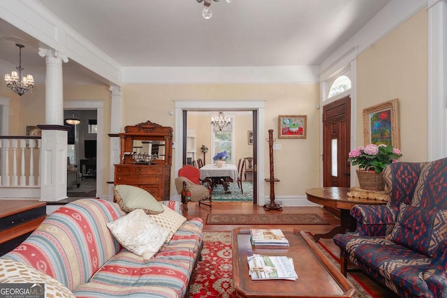 living room featuring a notable chandelier, wood-type flooring, and decorative columns