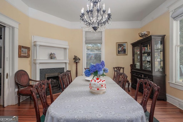 dining space with a notable chandelier, crown molding, a fireplace, and dark wood-type flooring