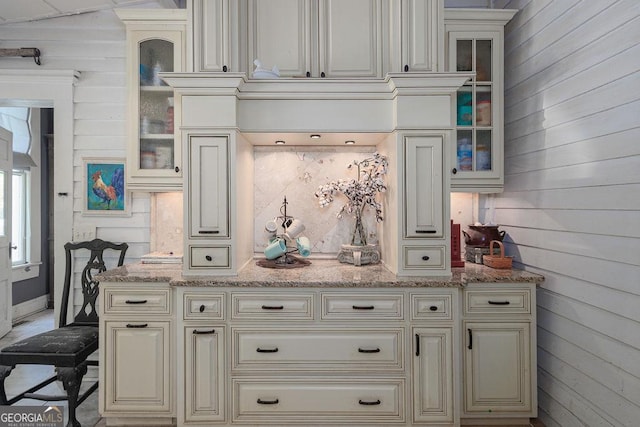 kitchen featuring light stone counters and wooden walls