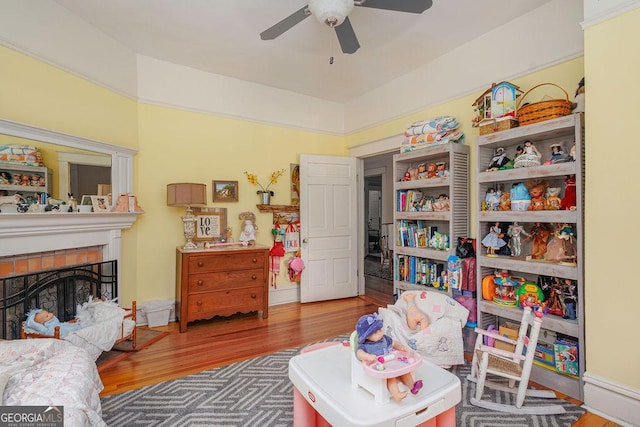 interior space with ceiling fan, wood-type flooring, and a brick fireplace