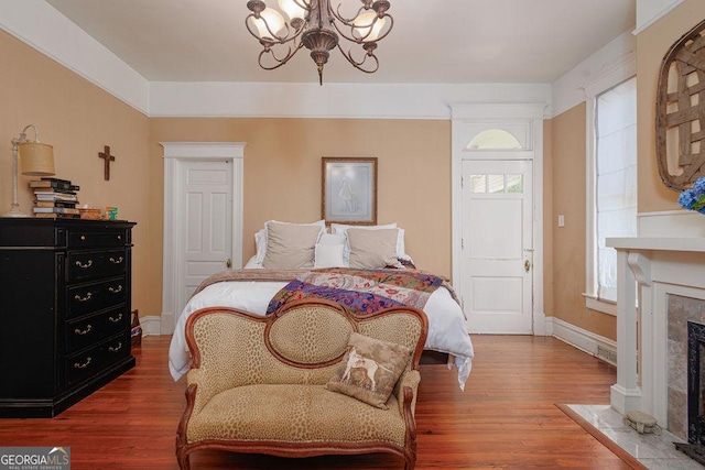 bedroom featuring hardwood / wood-style floors, a fireplace, and a chandelier